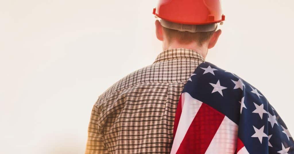 a man carries an American flag over his shoulder